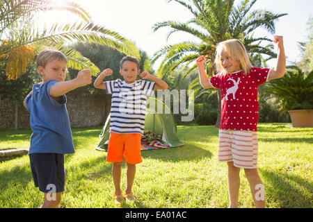 Drei Kinder im Garten, die Muskeln Stockfoto