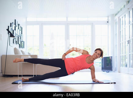 Mitte Erwachsene Frau praktizieren Yogaposition im Wohnzimmer Stockfoto