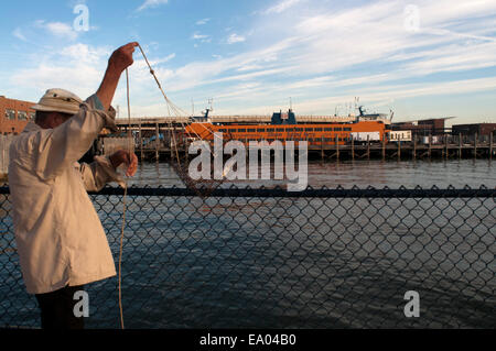 Ein Männer-Fische in die Anlegestelle der Fähre nach Staten Island. Die Staten Island Ferry, die Dichtung die Südspitze von Manhattan ist Staten Stockfoto