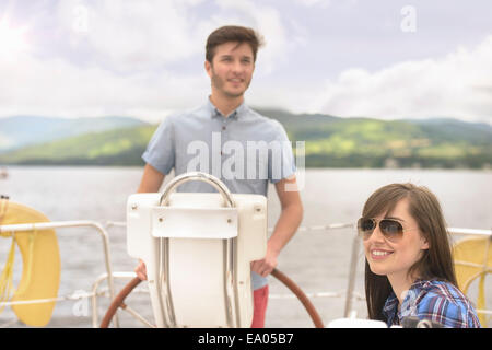 Junger Mann an der Spitze der Yacht mit Freundin in Sonnenbrillen Stockfoto