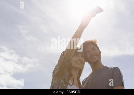 Junges Paar unter Selbstportrait auf Handy unter strahlend sonnigen Himmel Stockfoto