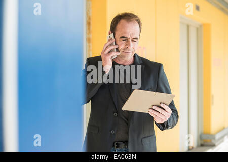 Reifer Mann auf Smartphone mit digital-Tablette Stockfoto