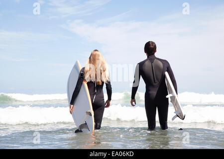 Junges Paar zu Fuß zum Meer halten Surfbretter, Rückansicht Stockfoto