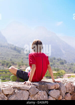 Junge sitzt auf Stein Wand anzustarren Ansicht, Mallorca, Spanien Stockfoto