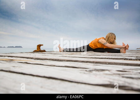 Mitte Erwachsene Frau praktizieren Yoga auf hölzernen See pier Stockfoto