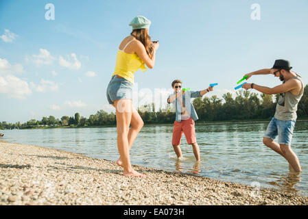 Junge Männer spielen mit Wasserpistolen in See Stockfoto