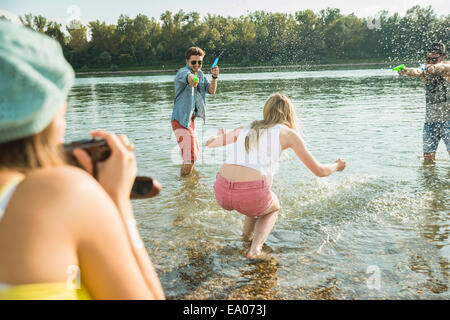 Freunde spielen mit Wasserpistolen in See Stockfoto