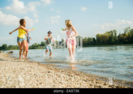 Freunde spielen mit Wasserpistolen in See Stockfoto