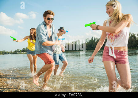 Freunde spielen mit Wasserpistolen in See Stockfoto