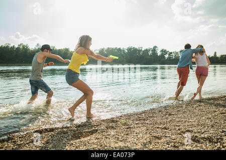 Freunde spielen mit Wasserpistolen in See Stockfoto