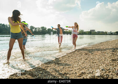 Freunde spielen mit Wasserpistolen in See Stockfoto