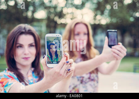 Zwei junge Freundinnen nehmen Selfie auf Smartphones im Einklang Stockfoto