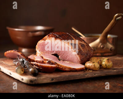 Weihnachtsessen. Muscavado Zucker Gammon gebacken serviert mit gerösteten Kartoffeln und Kräutern Stockfoto