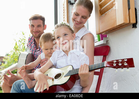 Mädchen spielen Gitarre mit Familie Stockfoto