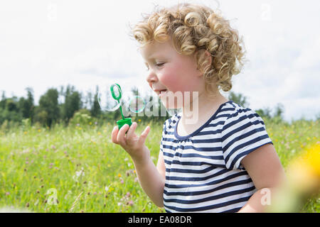 Mädchen bläst Luftblasen im Feld Stockfoto