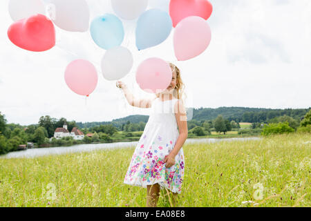 Mädchen halten Ballons im Feld Stockfoto