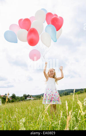 Mädchen halten Ballons im Feld Stockfoto