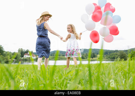 Mutter und Tochter im Feld mit Luftballons Stockfoto