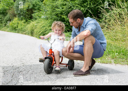 Mädchen reiten Dreirad mit Vater Stockfoto