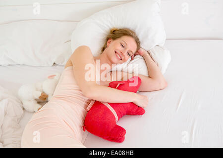 Mitte Erwachsene Frau auf Bett halten Stofftier liegend