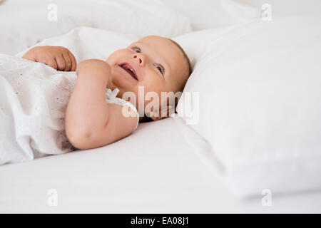 Babymädchen auf Bett liegend Stockfoto