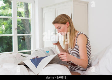 Mitte erwachsenen Frau sitzt im Bett und Las Zeitung Stockfoto