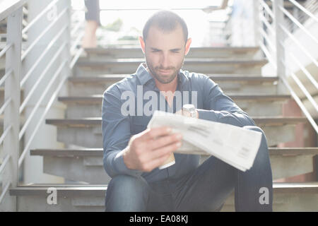 Geschäftsmann lesen Zeitungen auf Treppe Stockfoto