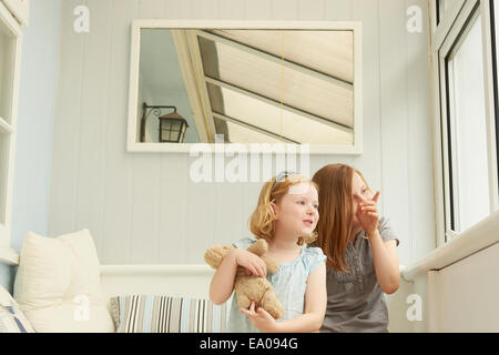 Zwei Schwestern zeigen und Blick aus Fenster Ferienwohnung Stockfoto