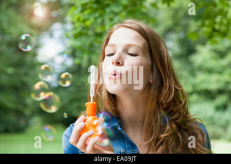 Junge Frau bläst Seifenblasen im Garten Stockfoto