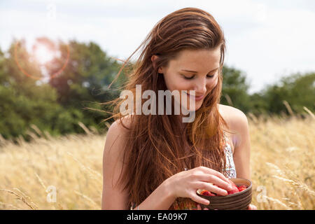 Junge Frau mit Schale mit frischem Obst im Feld Stockfoto