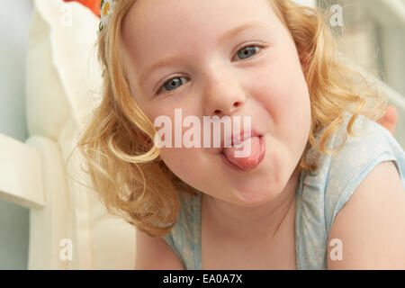 Porträt von Mädchen liegend auf Sitz Zunge heraus Stockfoto