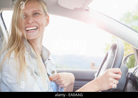 Junge Frau lächelnd hinter Rad des Autos Stockfoto