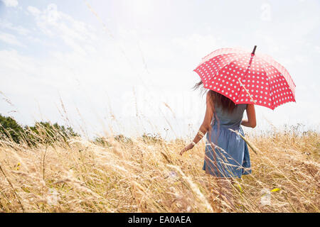 Junge Frau im Feld mit Regenschirm Stockfoto