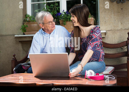 Junge Frau mit Laptop mit Großvater Stockfoto