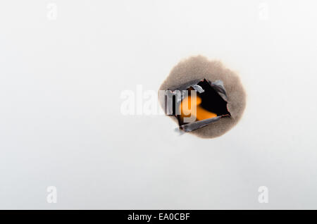 Brennt ein Loch durch ein weißes Blatt Papier mit schwarzen hinter Stockfoto