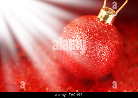 Weihnachts-Dekoration mit rot glänzenden Tand auf rotem Grund aus Glitzer und funkeln im Licht Stockfoto