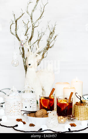 Weihnachten-Komposition mit Glühwein, Walnüsse, Kerzen und weiße Vintage Dekorationen. Weiße Hirsche im Hintergrund. Flachen Dof. Stockfoto
