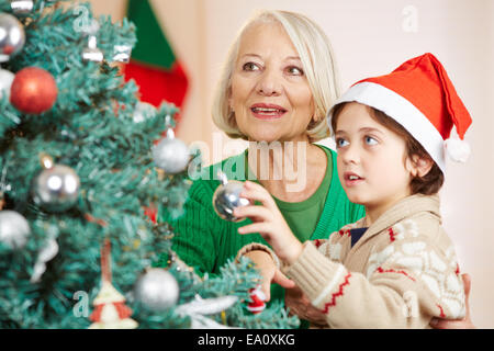 Junge und Oma hängen zusammen Christbaumkugeln auf einem Baum Stockfoto