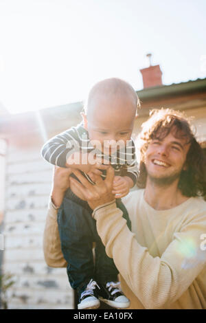 Vater Sohn in Armen neben Haus hochhalten Stockfoto