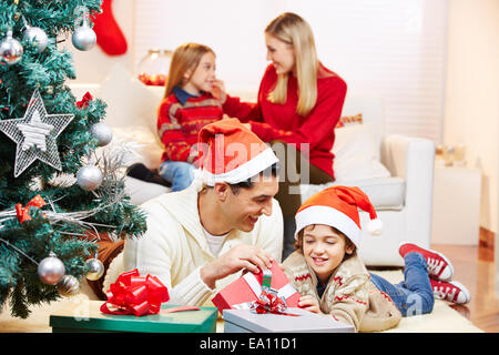 Vater und Sohn mit Geschenken an Heiligabend mit Mutter und Tochter auf sofa Stockfoto