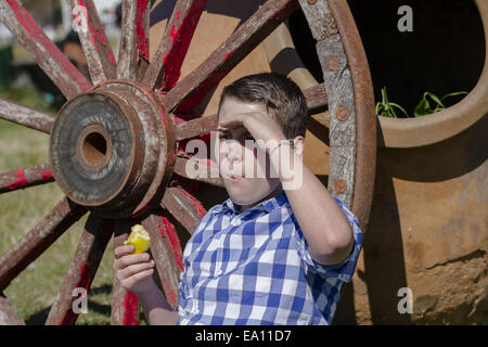 junger Cowboy liegen neben einem Wagenrad Stockfoto