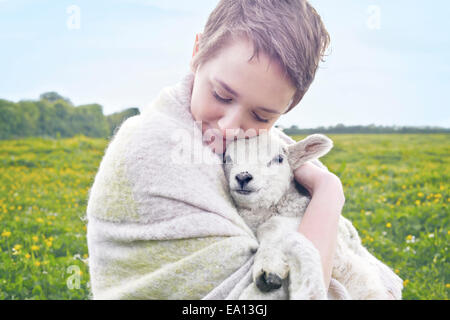 Porträt der jungen Frau im Feld mit Lamm und in Decke gehüllt Stockfoto