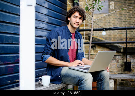 Mann mit Laptop auf Bank Stockfoto