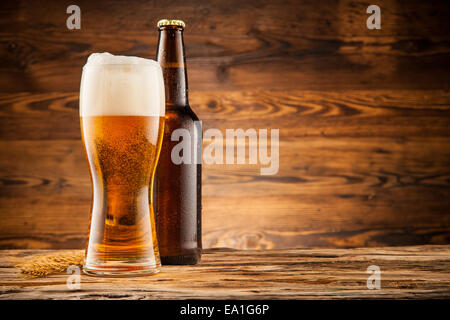 Glas und Flasche Bier mit Ähren auf Holzbohlen Stockfoto