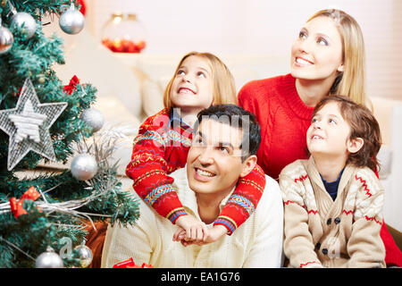 Familie und Kinder betrachten geschmückter Weihnachtsbaum im Wohnzimmer Stockfoto