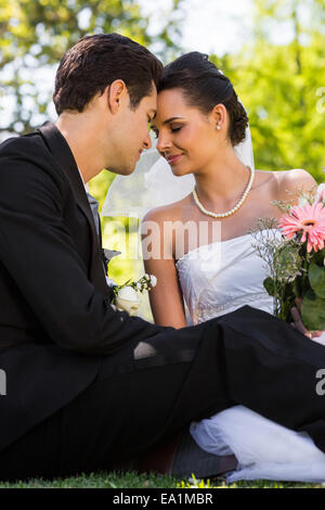 Romantisches Brautpaar sitzen im park Stockfoto