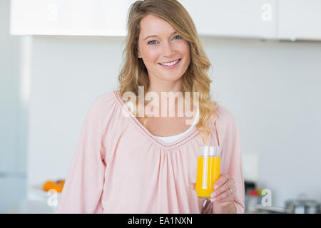 Frau mit Orangensaft in Küche Stockfoto