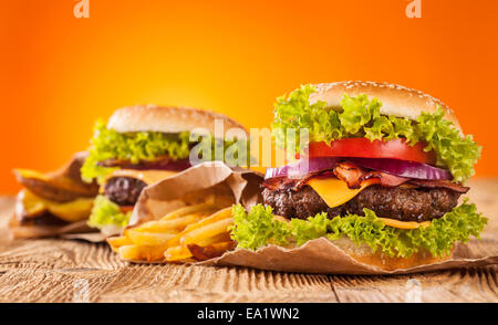 Leckere Hamburger auf Holz mit orangem Hintergrund Stockfoto