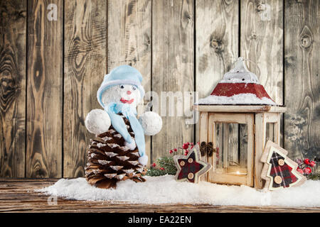 Weihnachten-Stillleben mit Laterne, Laterne und Schneemann. Holzbohlen als Hintergrund Stockfoto