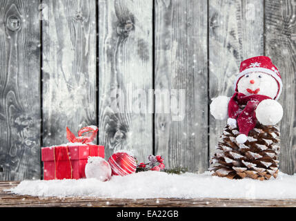 Weihnachten-Stillleben mit Laterne, Schneemann, Geschenke und Kugeln. Holzbohlen als Hintergrund Stockfoto